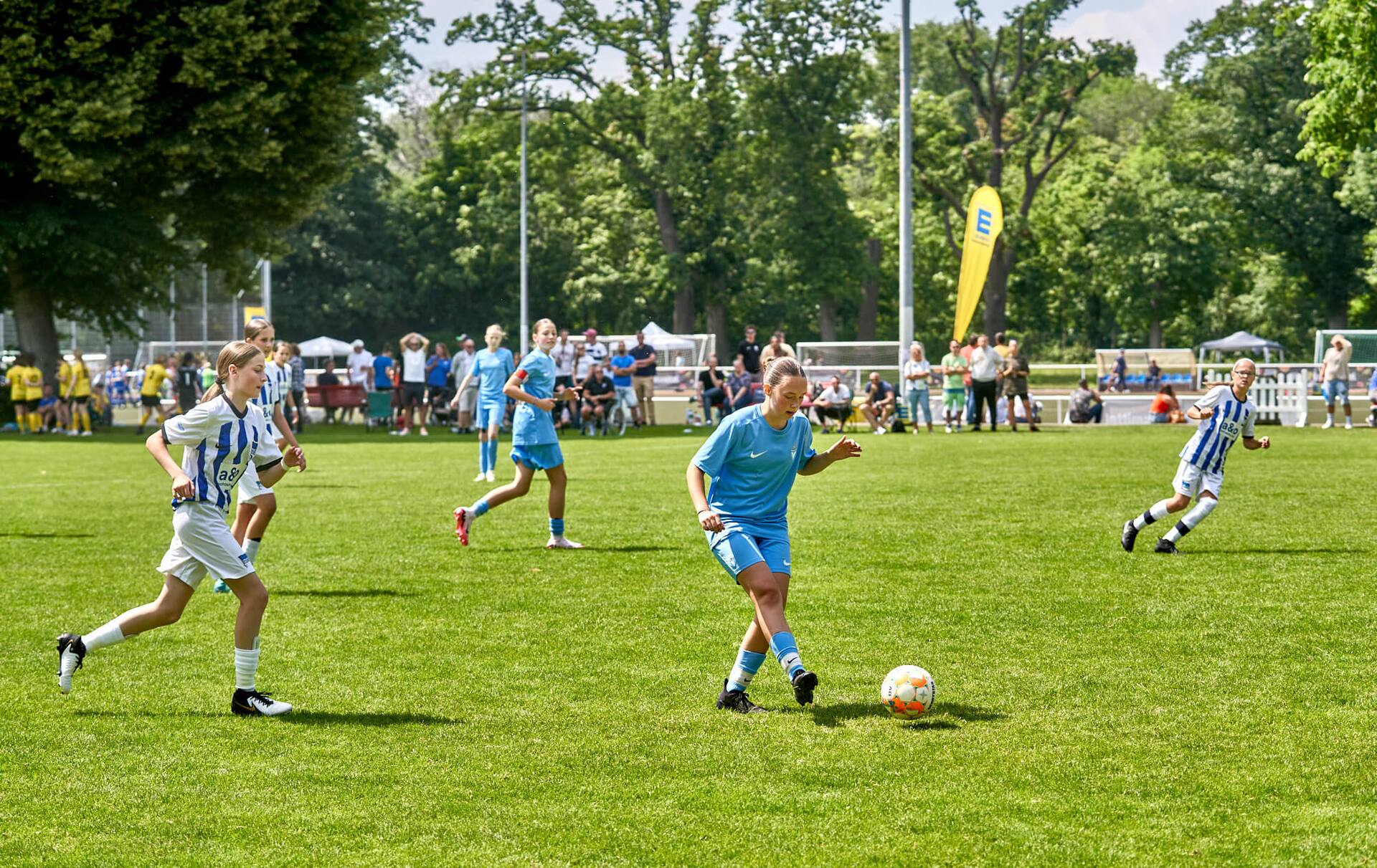 Eine Jugend-Fußballspielerin in blau spielt einen Pass mit der Innenseite ihres rechten Fußes.
