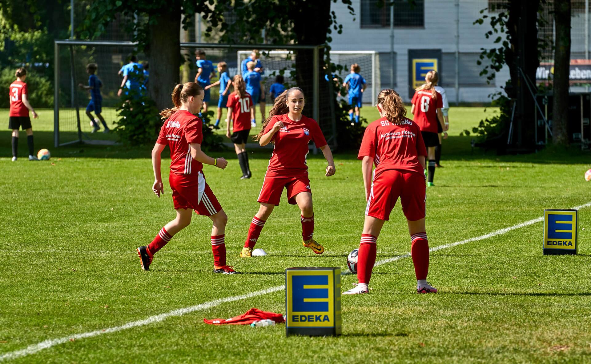 Aufwärmübungen bei einem weiblichen Jugend-Fußballteam in roten Trikots.