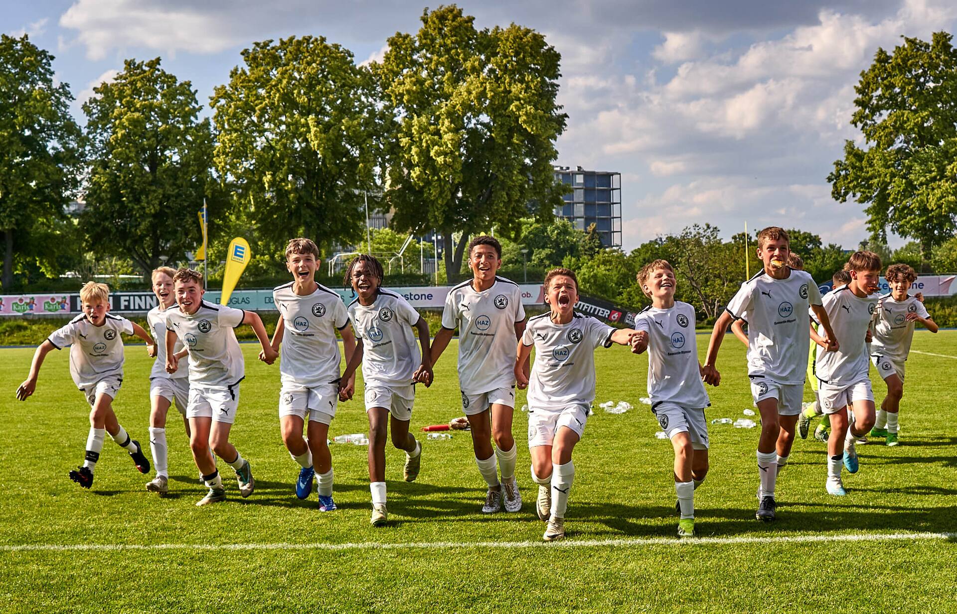 Kollektiver Jubel eines Jugend-Fußballteams in weißen Trikots.