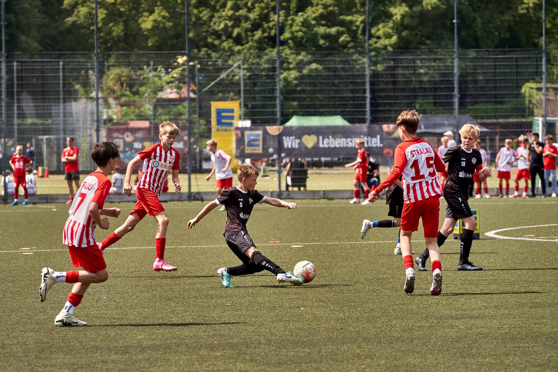 Ein Jugendspieler in schwarz schießt den Ball fast im Sitzen.