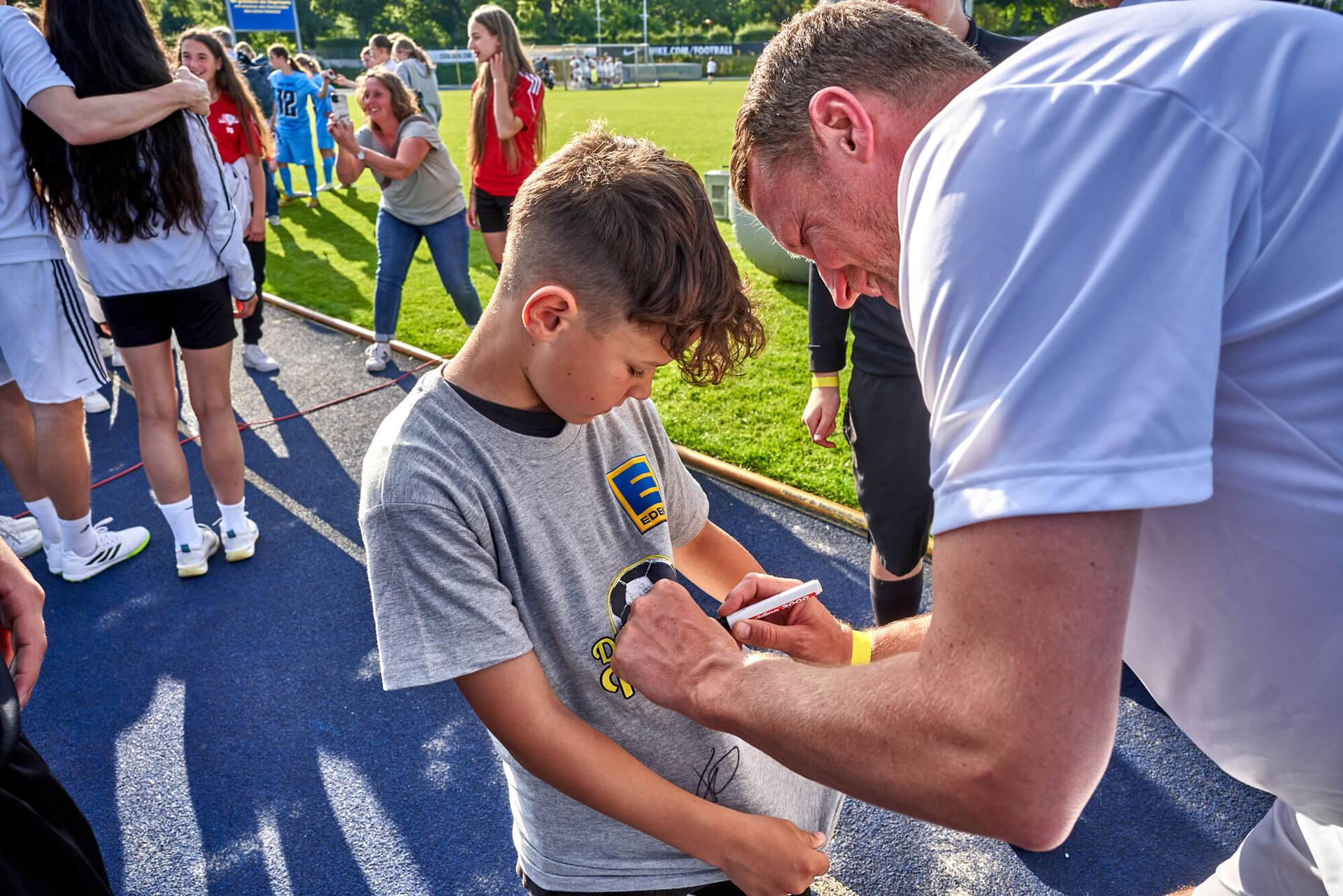 Ex-Profi Maik Franz signiert das T-Shirt eines jungen Fans.