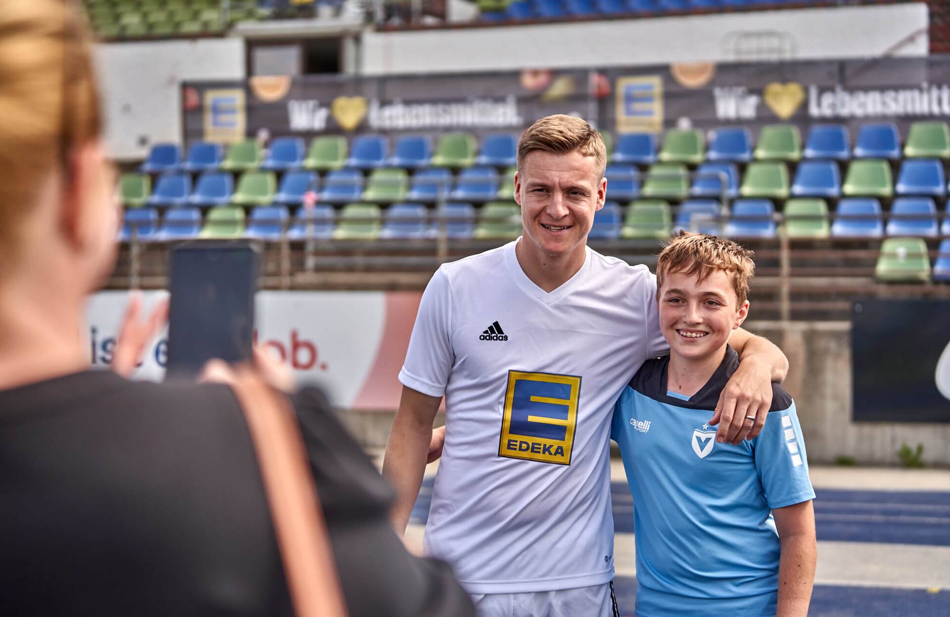 Eine Frau macht ein Handyfoto von einem Jungen mit Ex-Profi Felix Kroos.