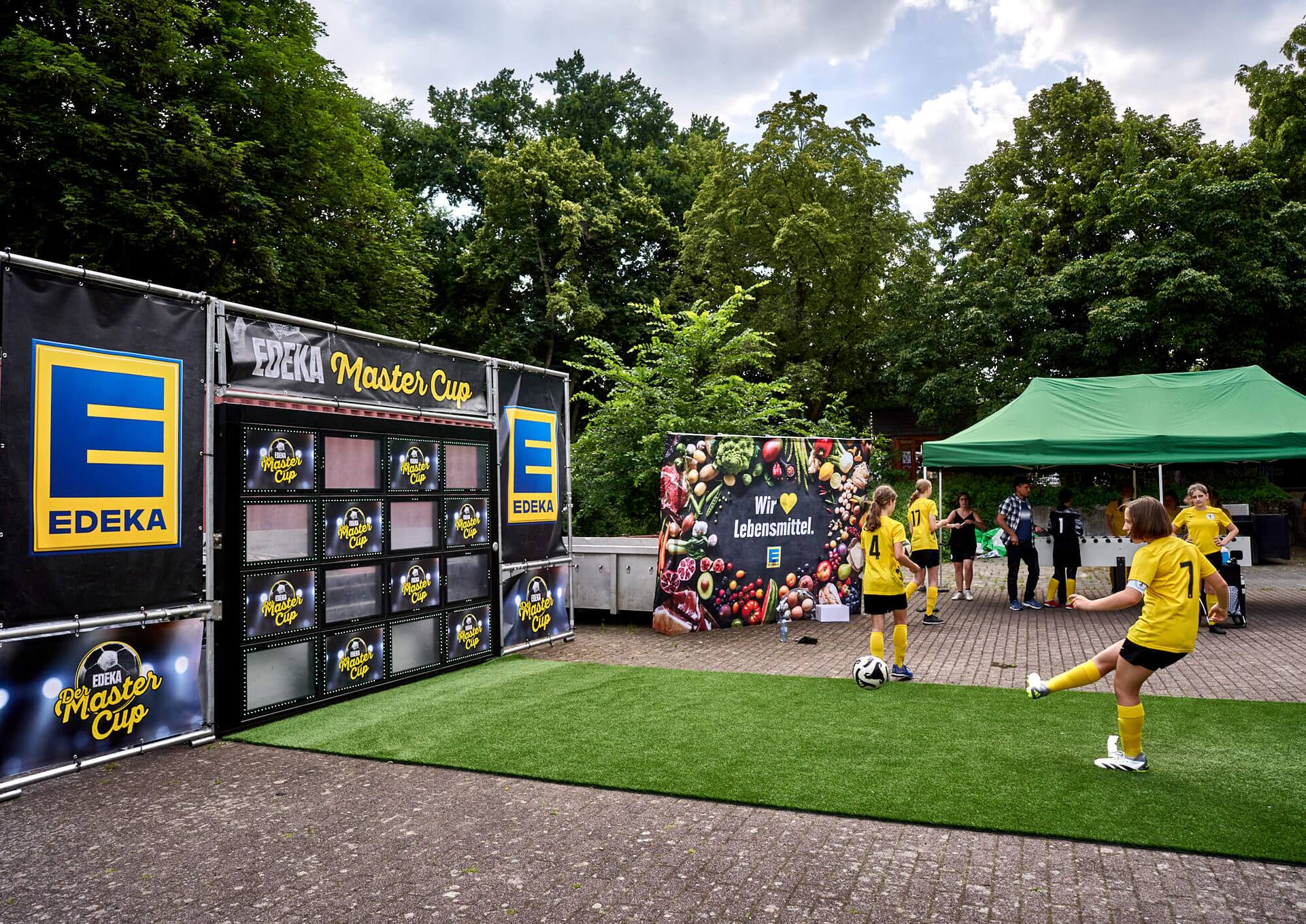 Ein Mädchen schießt auf eine Torwand, auf der EDEKA Master Cup steht.