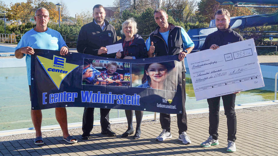 Das Bild zeigt fünf Mitarbeitende des EDEKA center Wolmirstedt und des Freibads mit dem Banner des Marktes und einem großen Spendenscheck.