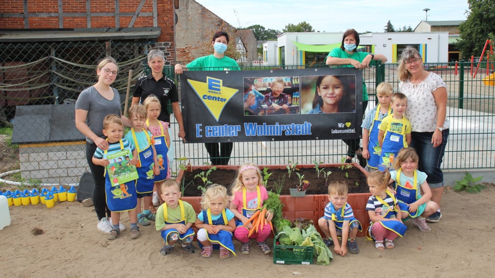 Das Bild ist ein Gruppenfoto mit allen Beteiligten vor dem neuen Gemüsebeet.