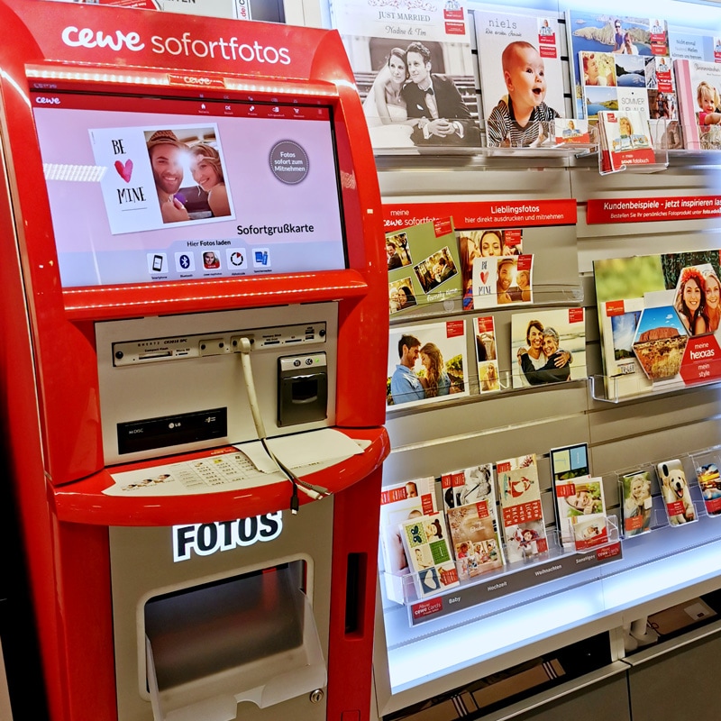 Das Bild zeigt den roten cewe Fotoautomat des Marktes.
