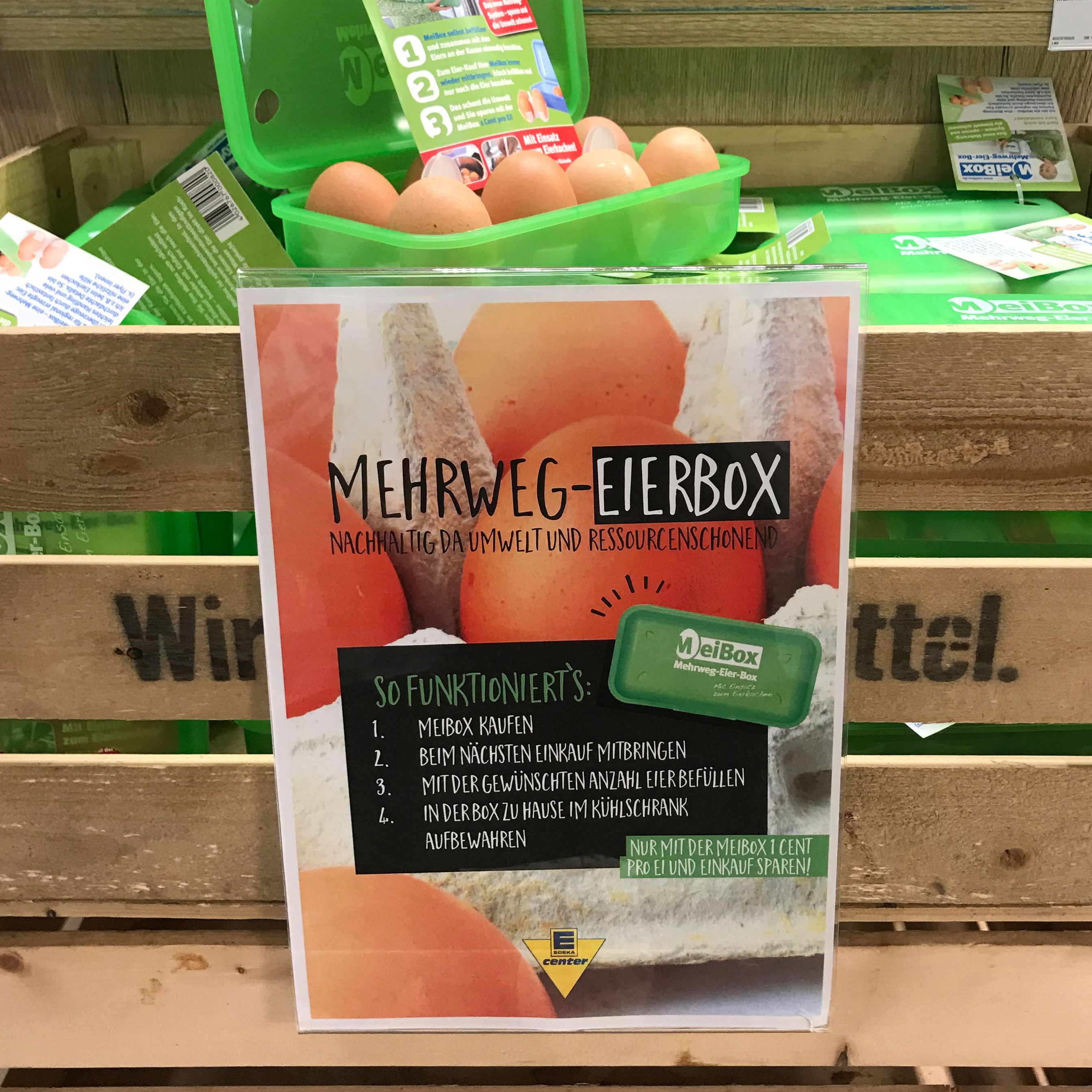Das Bild zeigt im vordergrund das Poster für die Mehrweg-Eierbox.