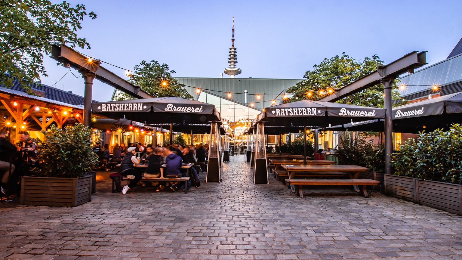 Innenhof der Ratsherrn Brauerei in Hamburg mit überdachten Bierbänken und Tischen.