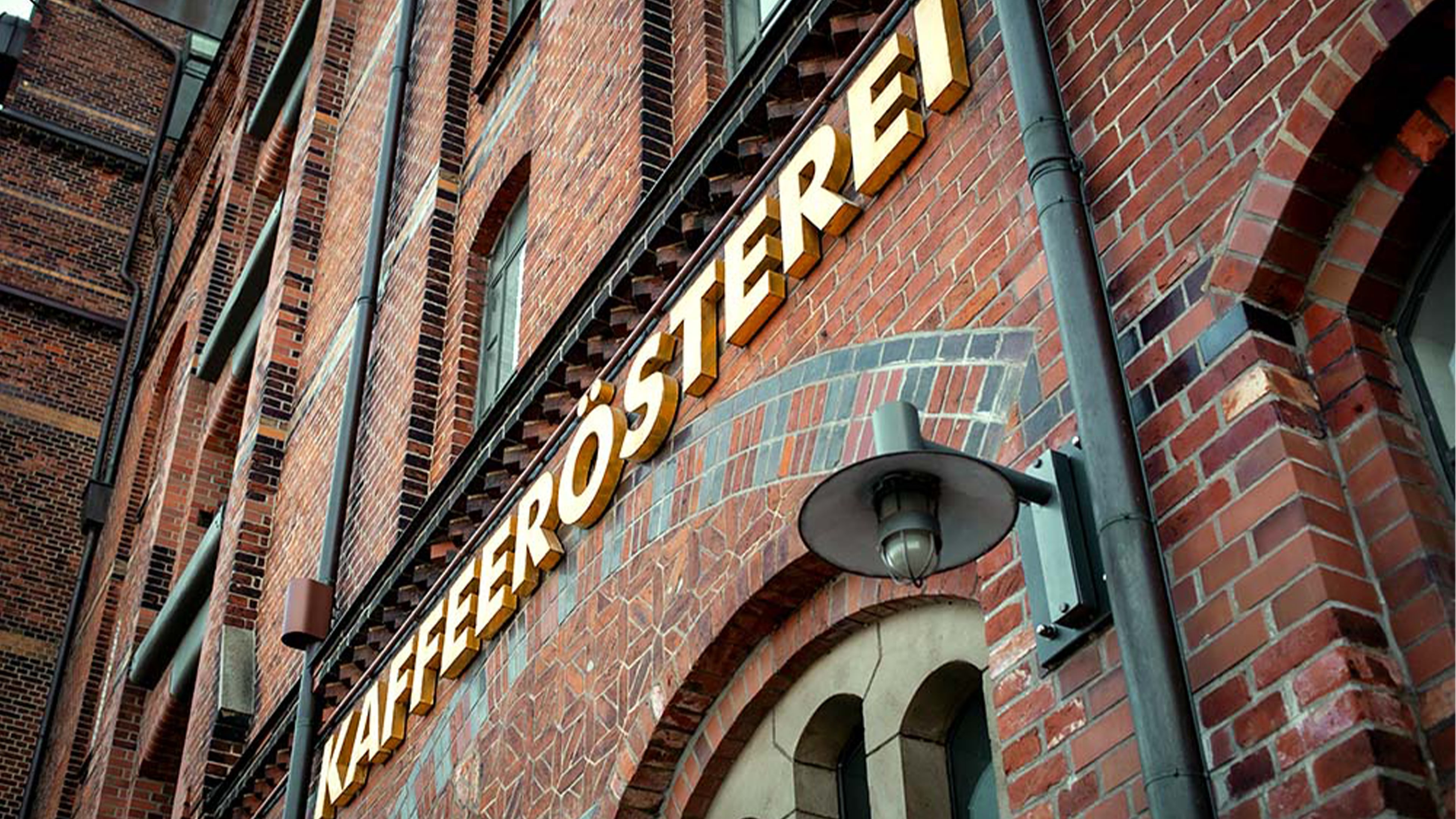 Rote Backsteinfassade, an der in goldener Schrift Kaffeerösterei steht.
