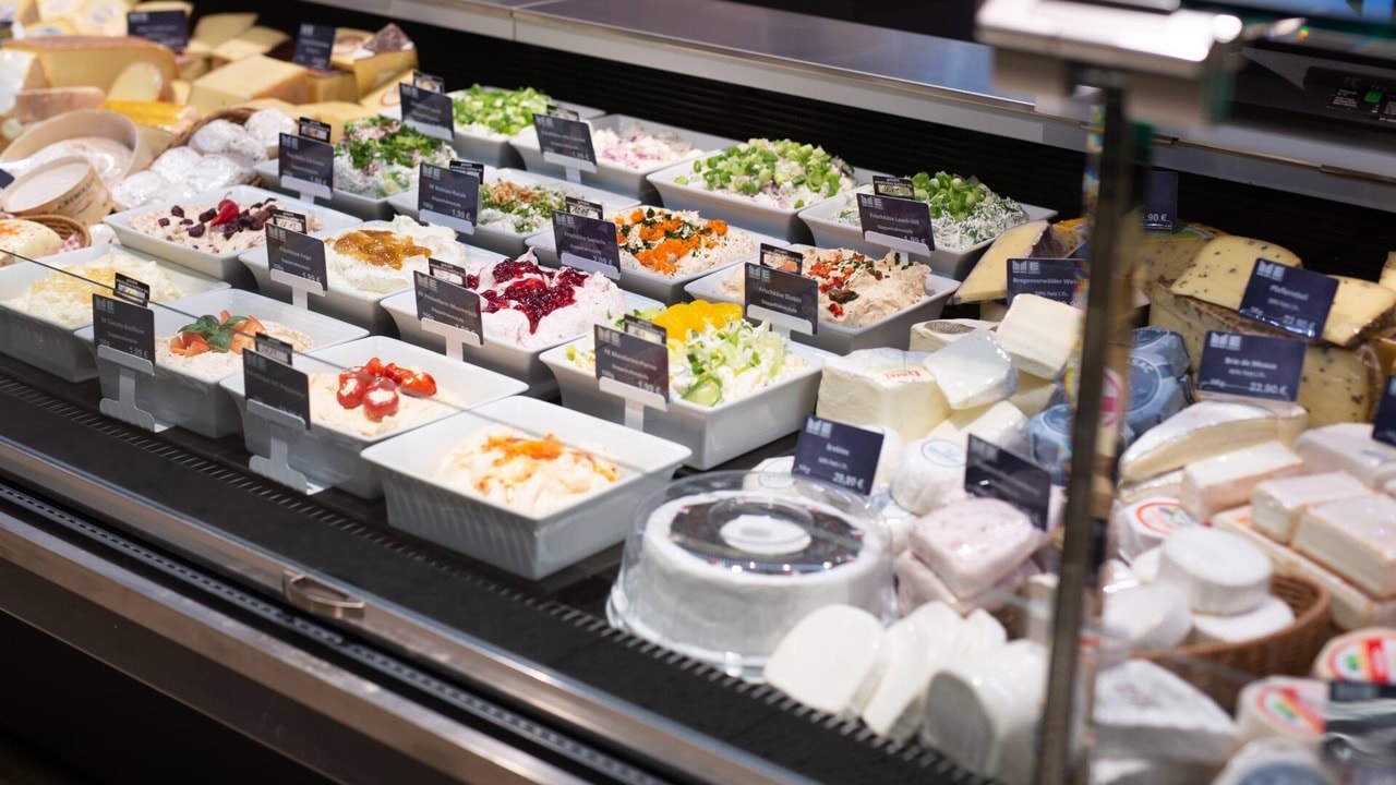 Auslage mit verschiedenen Frischkäsesorten in weißen viereckigen Keramikbehältern.