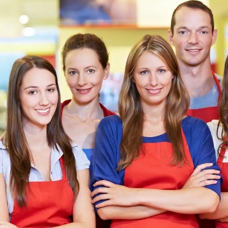 Vier junge Menschen mit roten Schürzen.