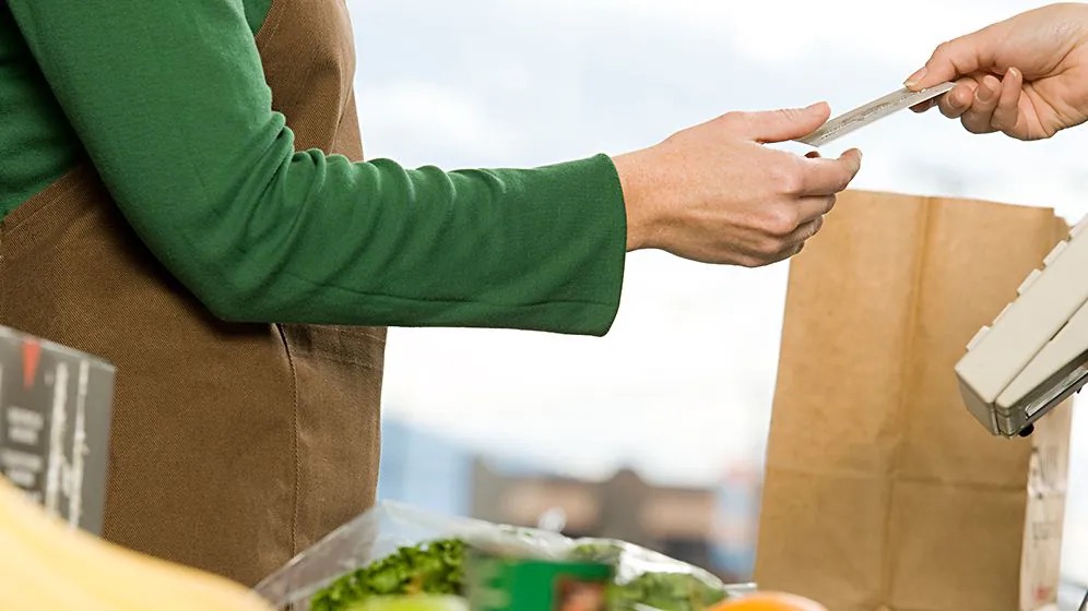 Zwei Personen reichen sich eine Bezahlkarte.