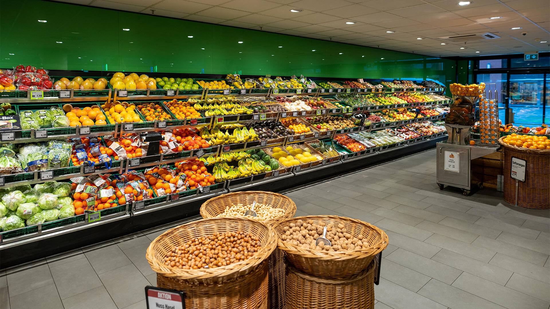 Obst- und Gemüseabteilung am Eingang des Marktes. In der Mitte des Raumes stehen Körbe mit Nüssen.