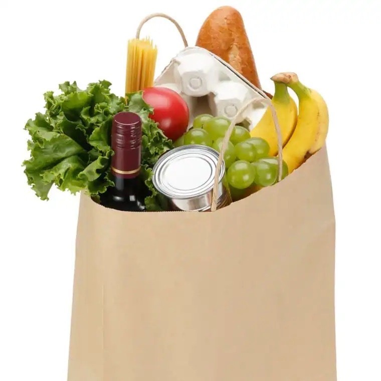 Zwei Papiertüten mit Lebensmitteln wie Möhren, Paprika und Wasser.