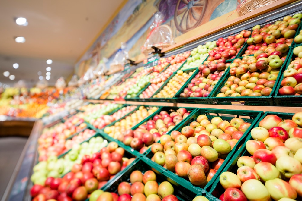 Obstregal mit kistenweise Äpfeln.