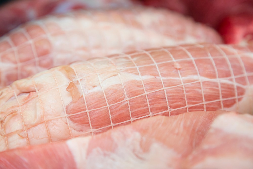 Rohes Stück Fleisch mit Bratennetz.