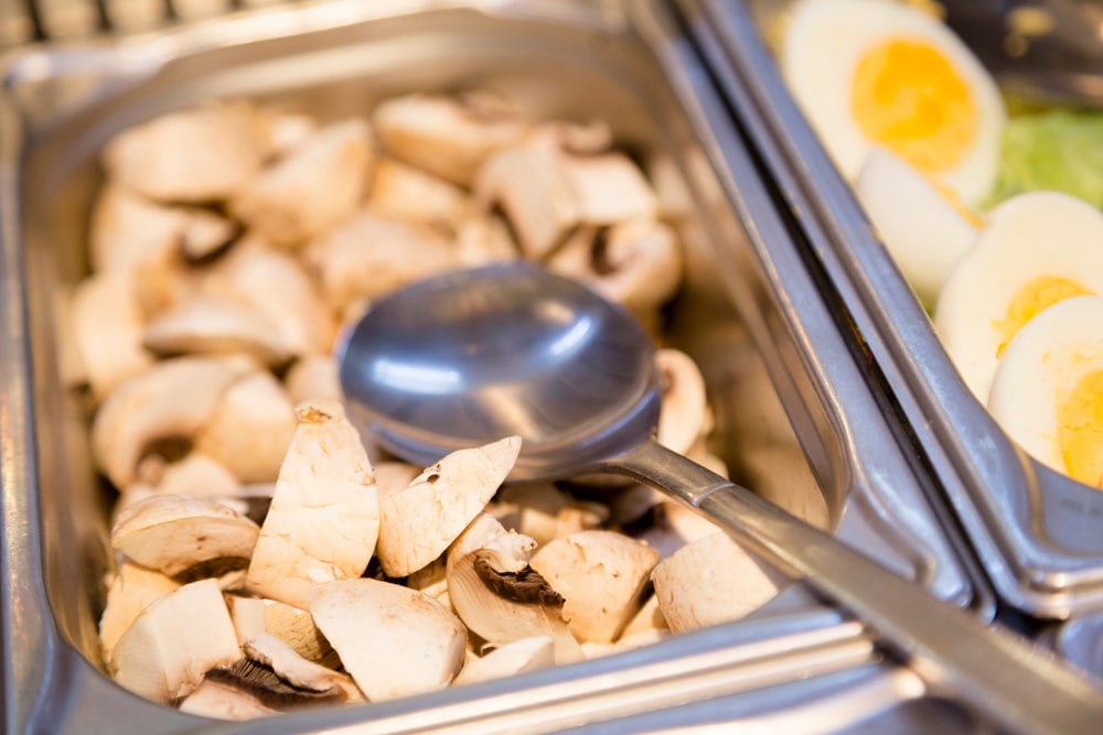 Edelstahl-Behälter mit geviertelten Champignons.