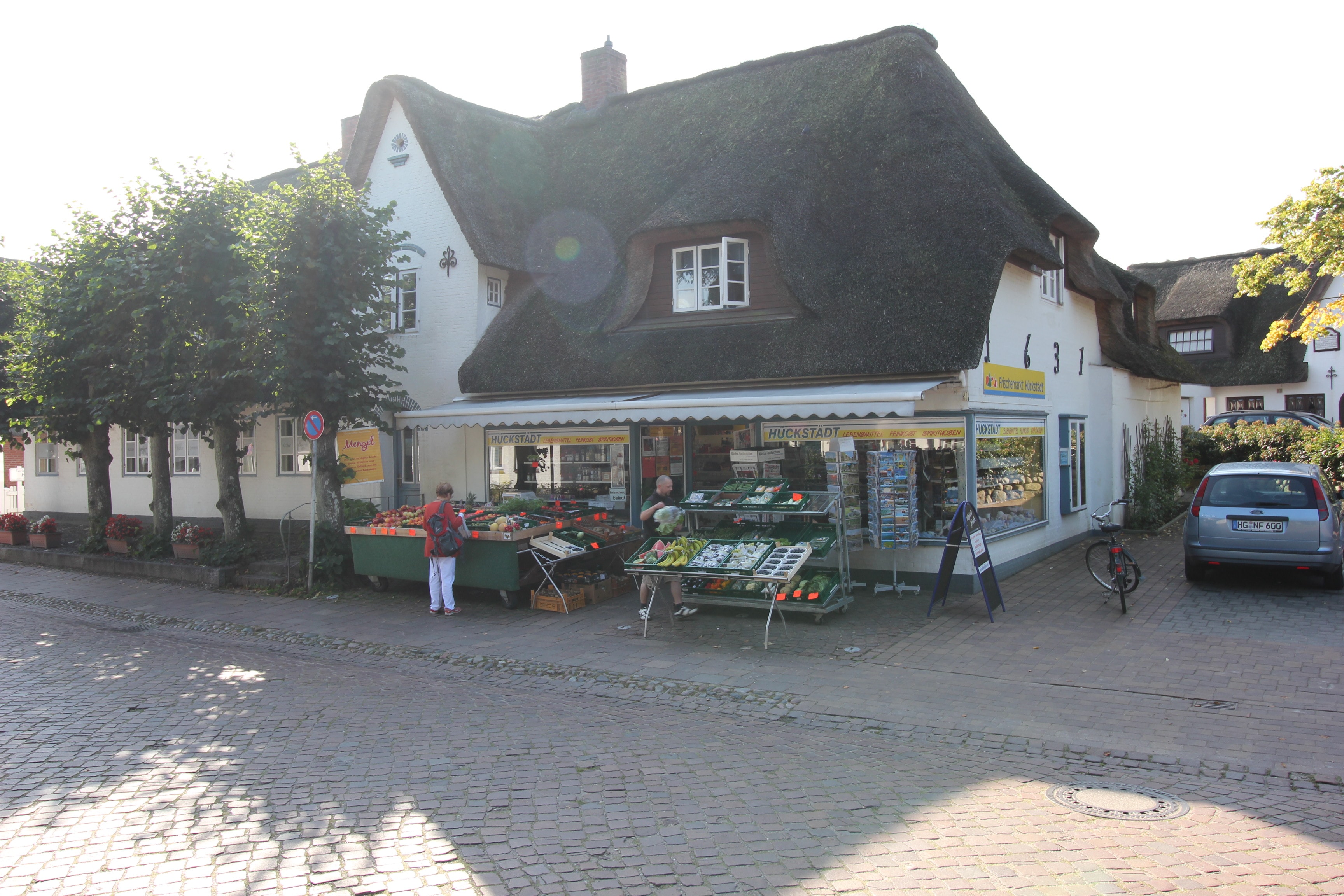 Außenansicht des reetgedeckten EDEKA-Marktes Hückstädt. Vor dem Markt sind Aufsteller für Gemüse.