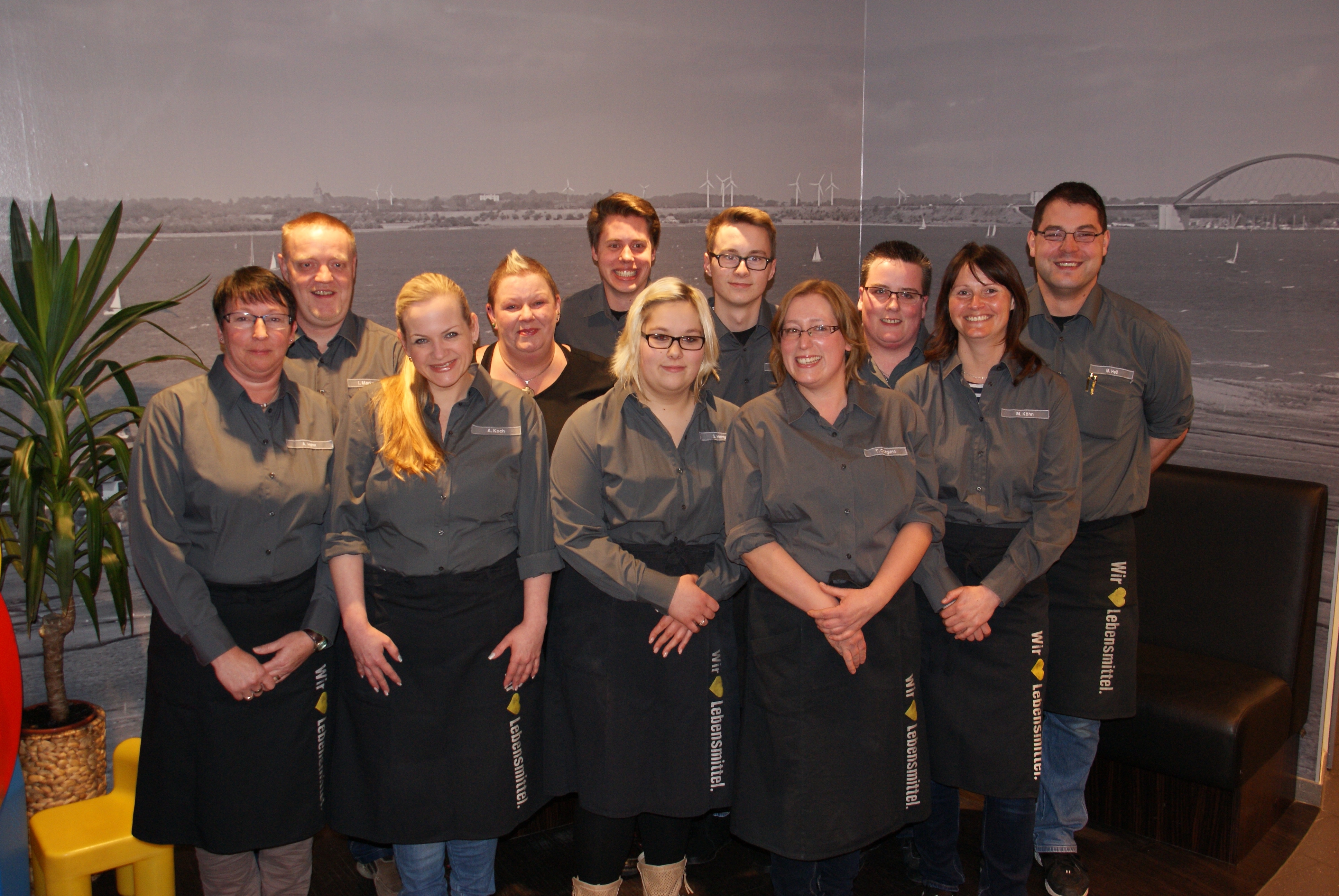 Gruppe von elf Personen in grauer Arbeitskleidung von EDEKA.