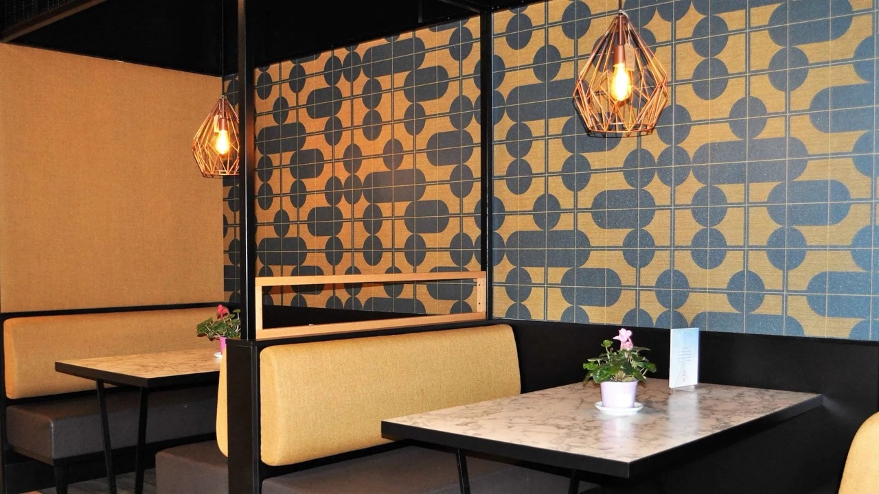 Zwei Cafétische mit einer gekachelten Wand im Hintergrund.