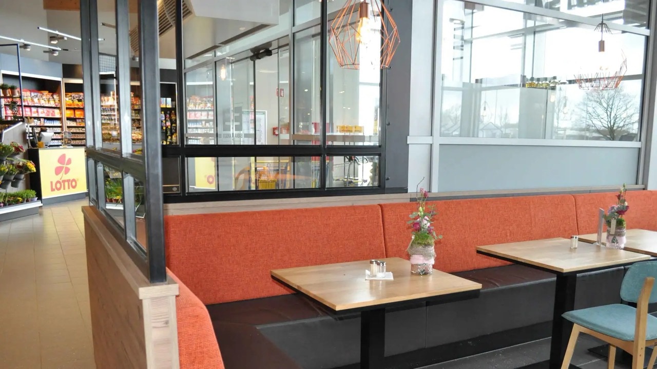 Rot gepolsterte Sitzbank im Eingangsbereich eines Cafés.