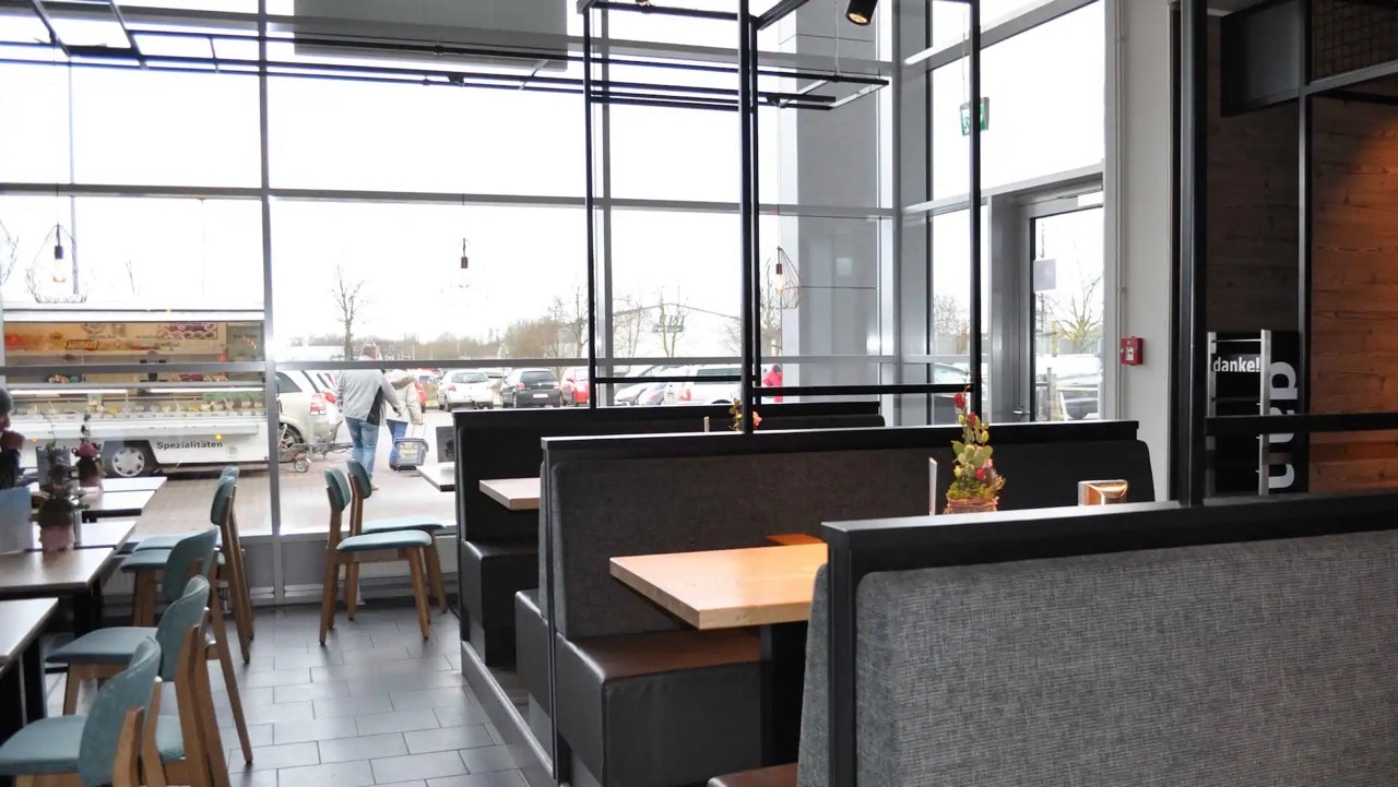 Grau gepolsterte Sitzbänke mit Tischen in einem Café.