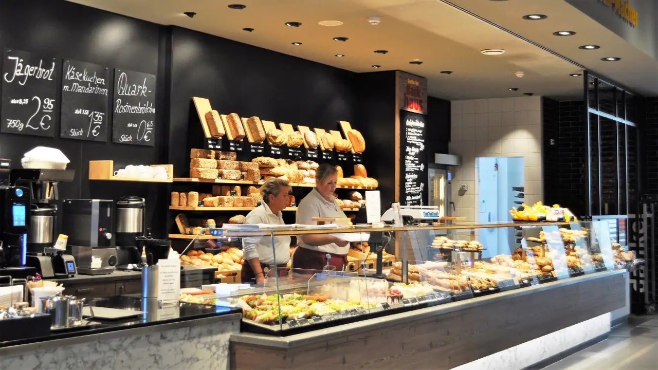 Bäckerei und Café mit Glasauslage und zwei Angestellten dahinter.