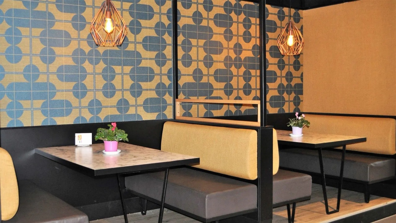 Tische und Sitzbänke in einem Café mit modern gekachelter Wand.
