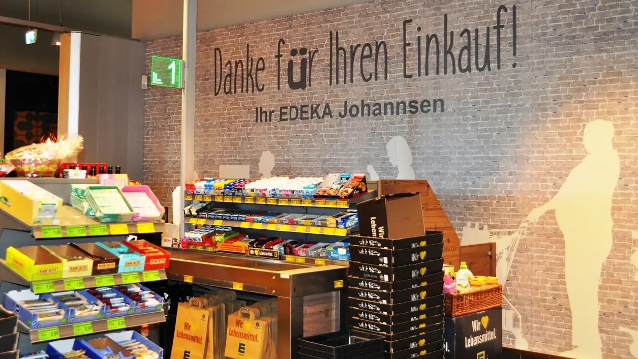 Gemauerte Wand im Kassenbereich mit der Aufschrift: Danke für Ihren Einkauf! Ihr EDEKA Johannsen.