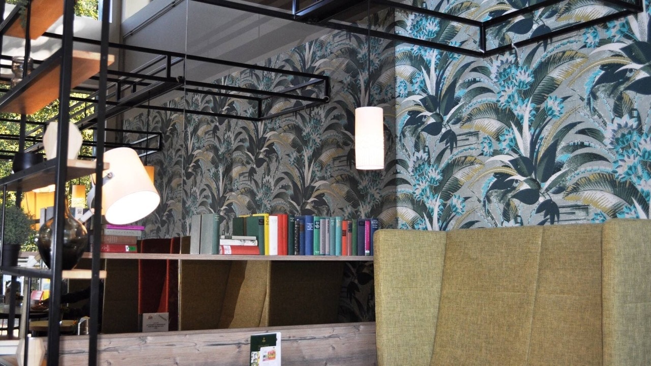 Cafébereich mit Polstermöbeln, Lampen und Bücherregalen.