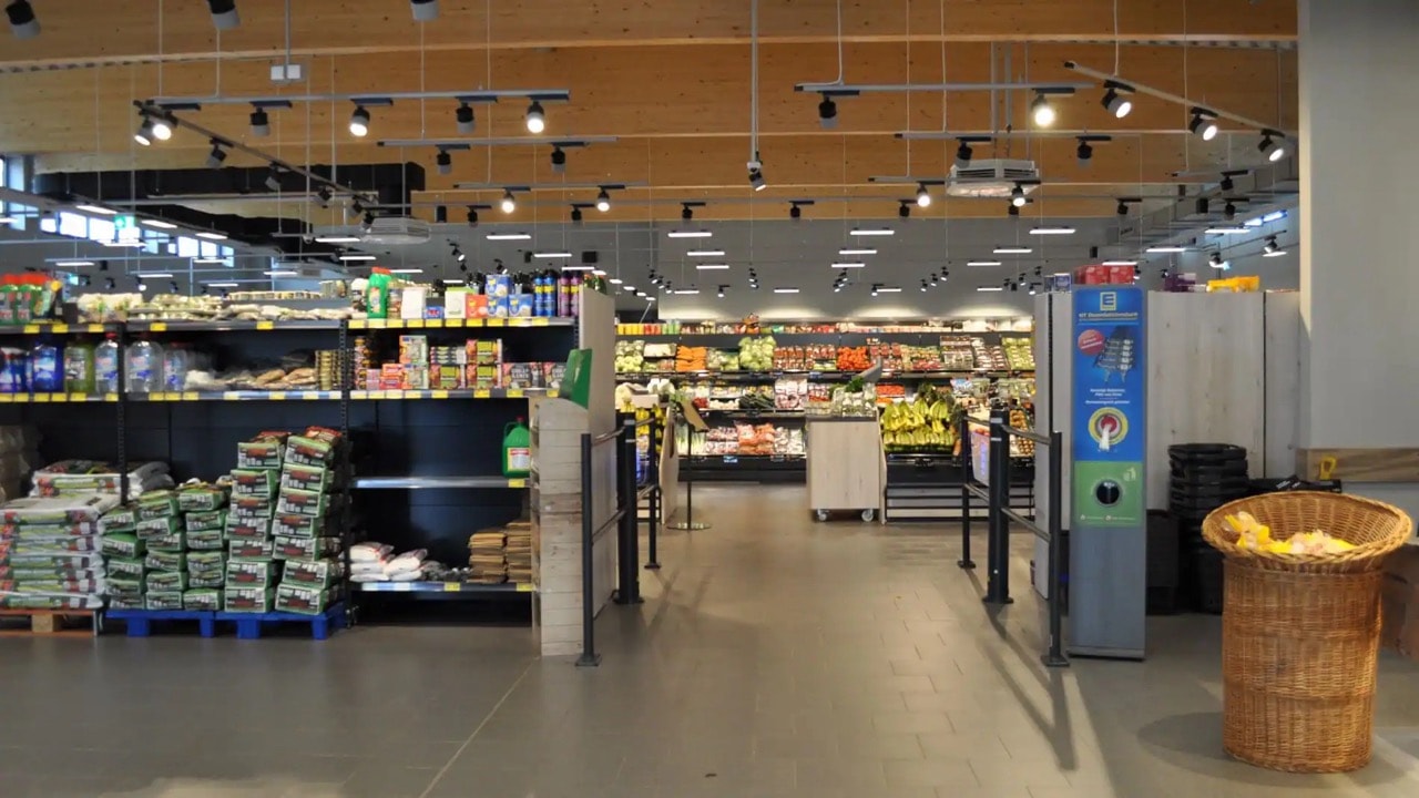 Vor dem Eingang im Inneren des Marktes steht ein Regal mit Blumenerde.