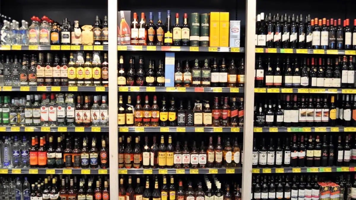 In drei Bereiche geteiltes Regal mit Spirituosen und Rotwein.