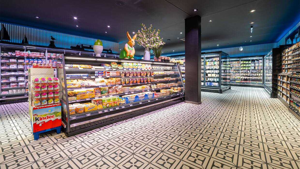 Verzierter Kachelboden im Inneren des EDEKA-Marktes mit freistehenden Kühlschränken.