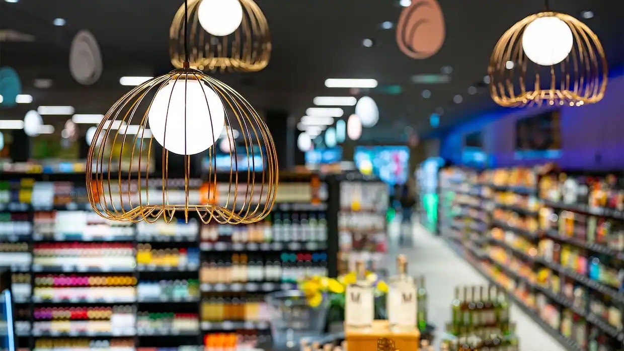Drei goldene Deckenlampen in einem EDEKA-Markt.