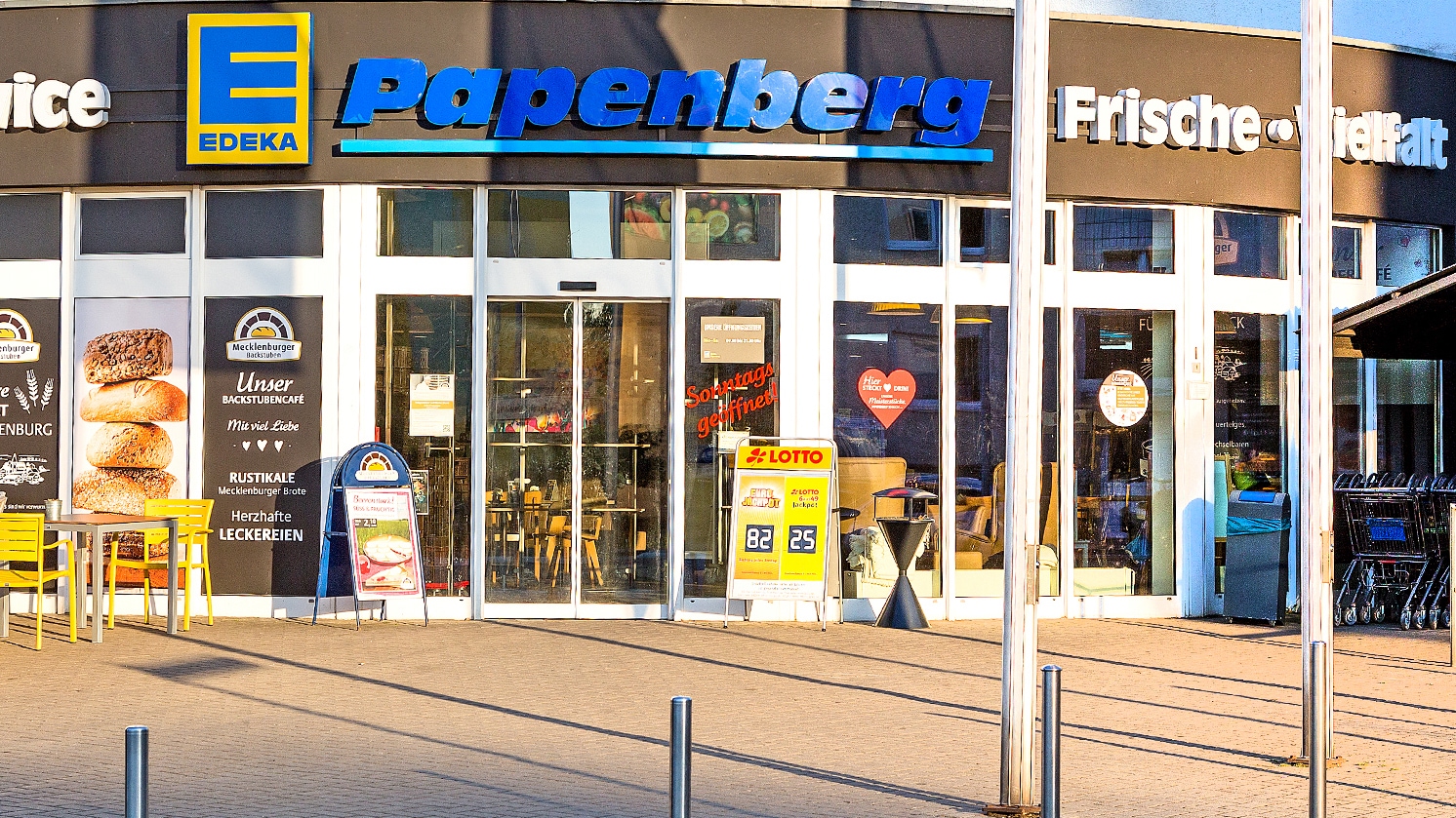 Der EDEKA Papenberg Eingang von außen im Sonnenschein.