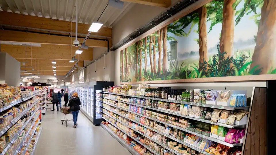 Über dem Regal für Öl un dTrockenfrüchte ist ein großes Wandbild mit Wald und einem Hochsitz.