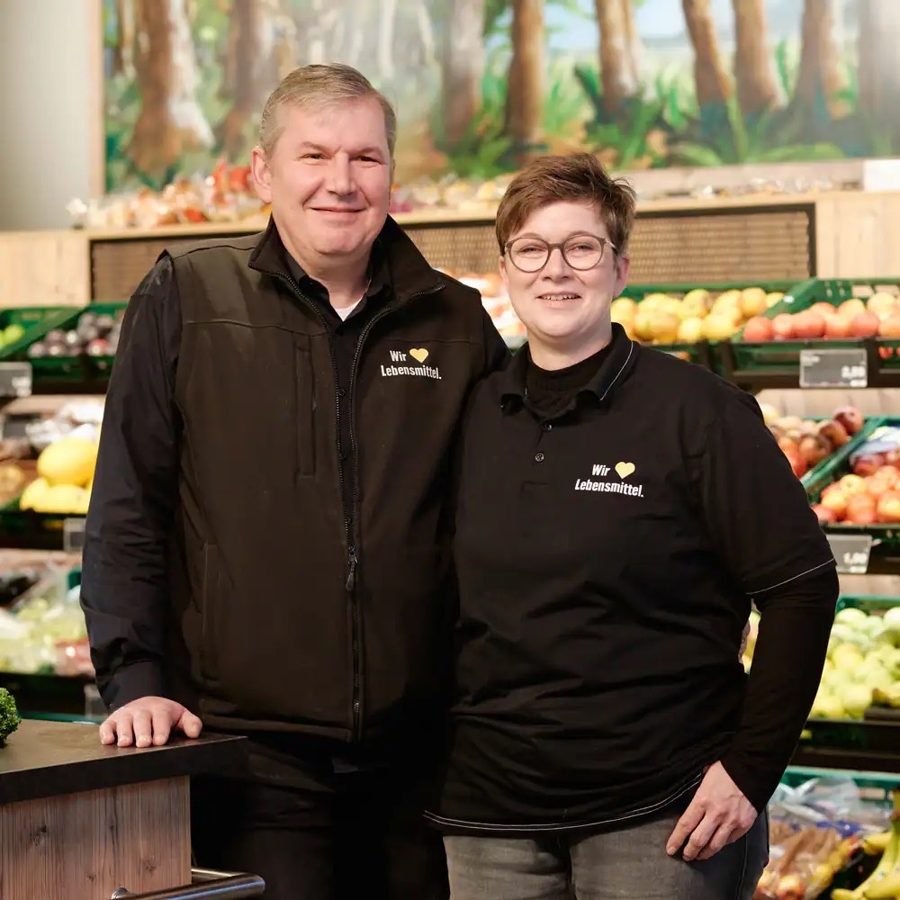 Mann und Frau in schwarzer EDEKA-Kleidung.