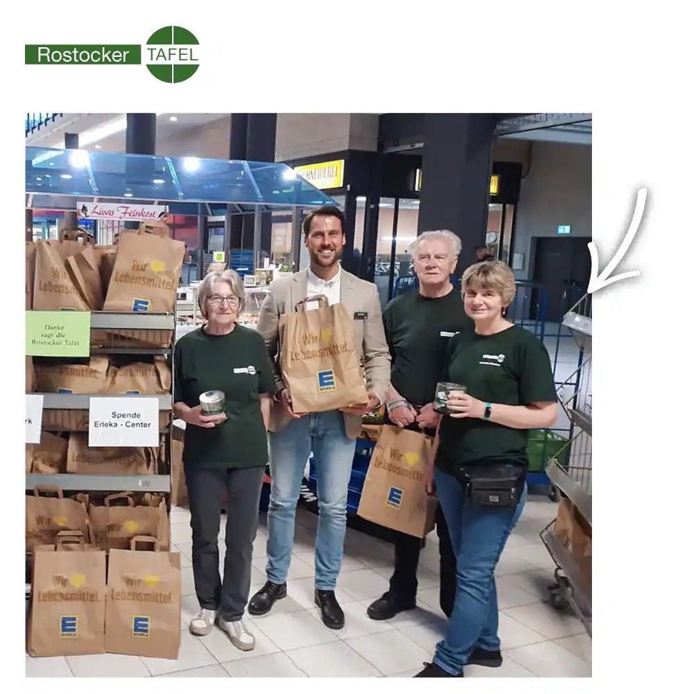 Vier Menschen mit einer Menge Papiertüten von EDEKA in einem Regal.