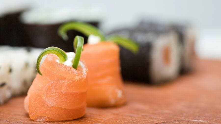 Lachsrolle aus der zwei grüne Gemüsestücke herausragen.