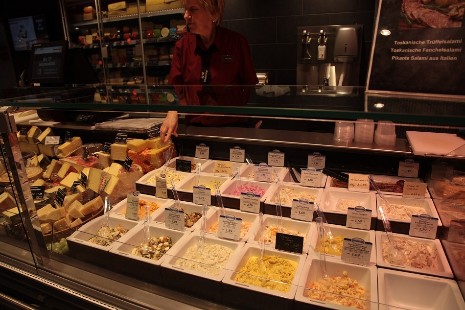 Salate in weißen Behältern in der Frischetheke.