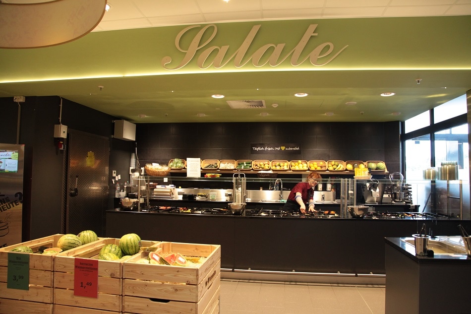 Schwarzer Tresen über dem in goldener Schrift das Wort „Salate" steht.