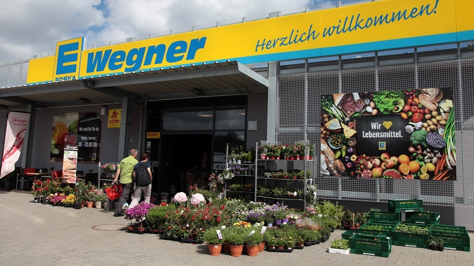 Eingangsbereich von außen mit Blumen im Sonnenschein.