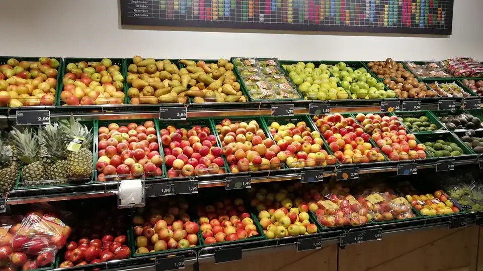 Auslage mit verschiedenen Apfelsorten sowie Kiwi und Ananas.