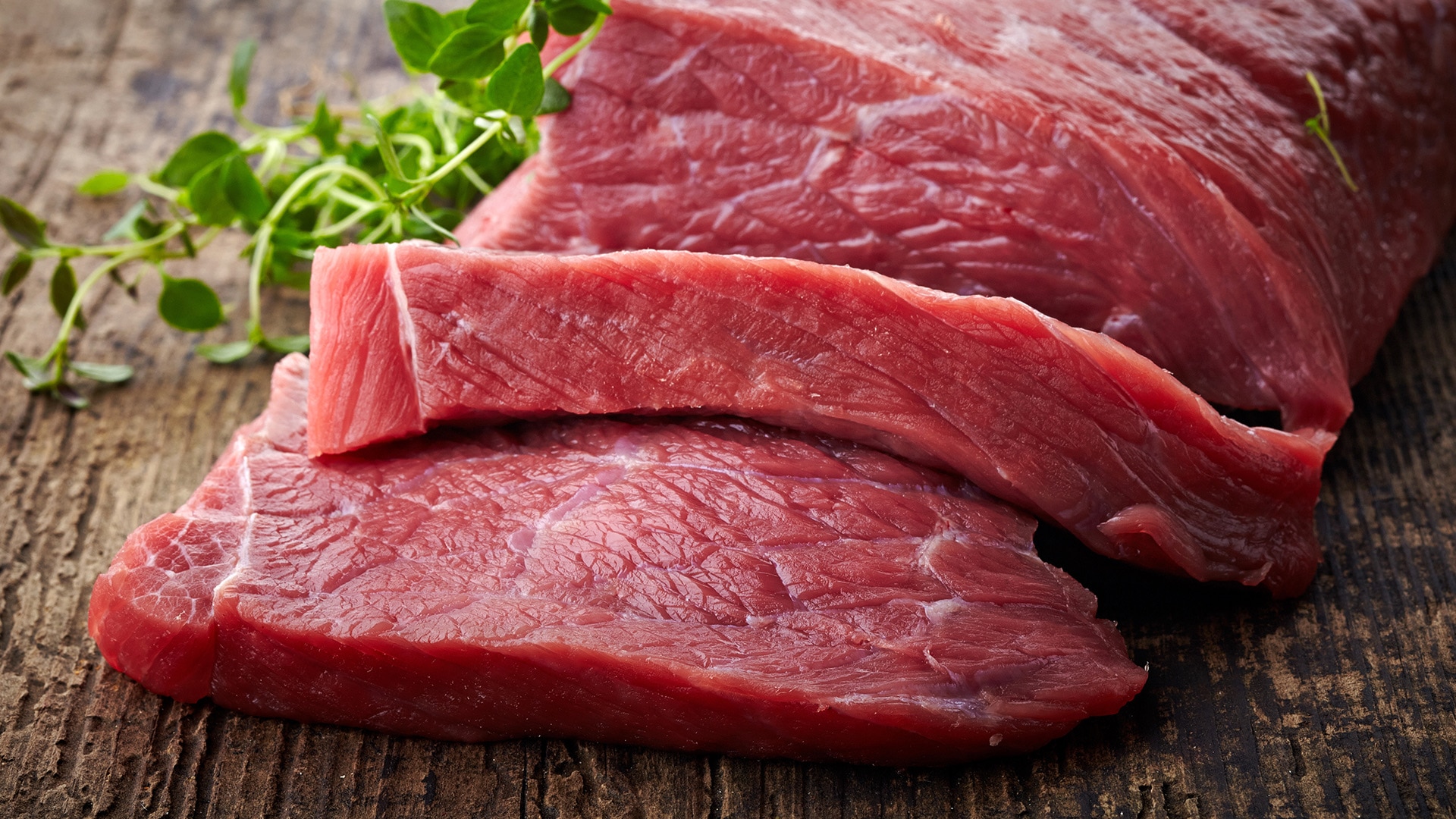 Ein rohes Stück rotes Fleisch, von dem zwei Scheiben abgeschnitten sind.