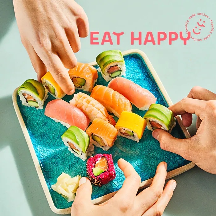 Drei Händen nehmen sich Sushi von einer Platte.