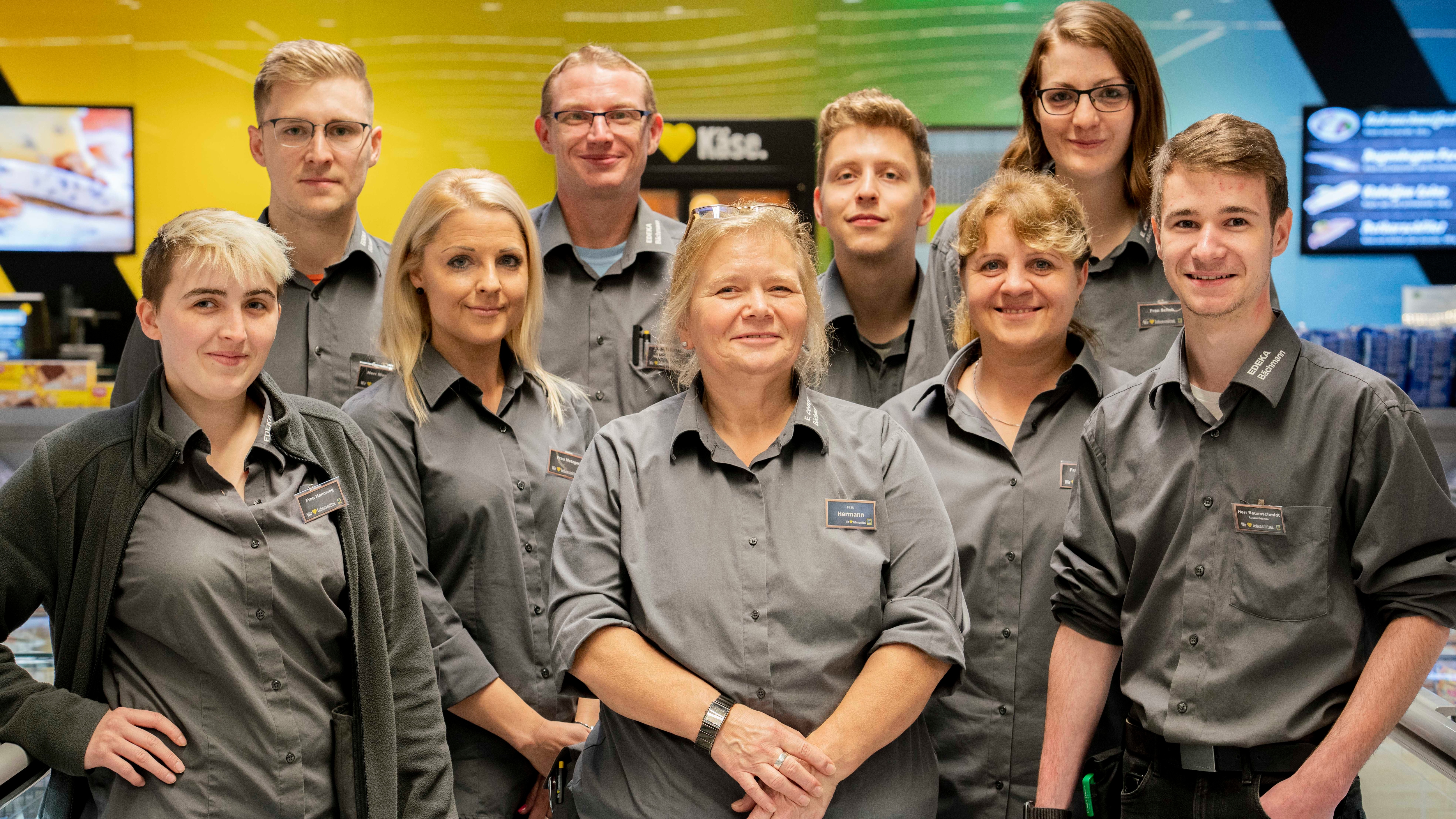 Ein Gruppenbild von neun Edeka-Mitarbeitern und Mitarbeiterinnen in Arbeitskleidung.