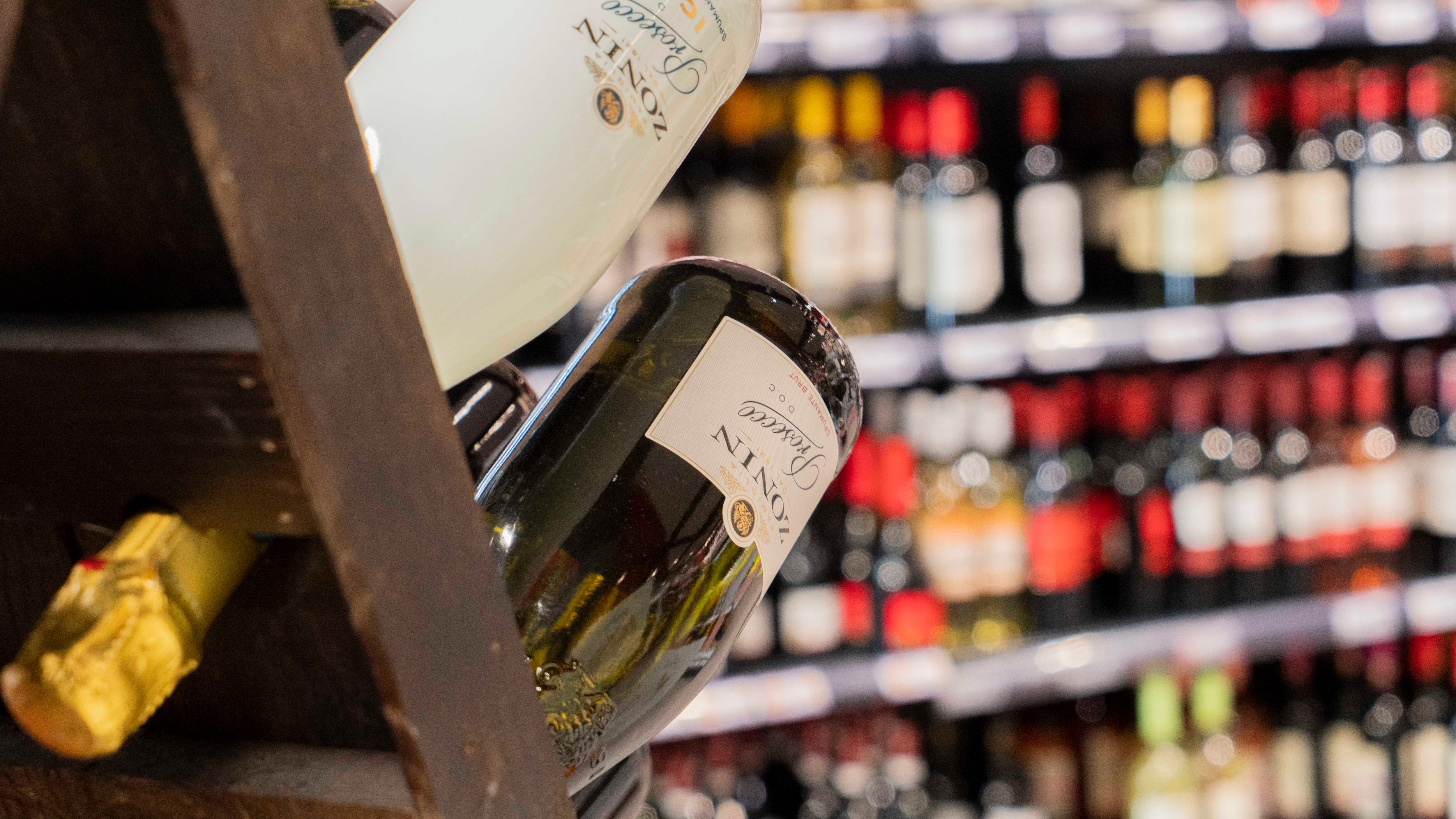 Nahaufnahme von zwei Prosecco Flaschen, die in einem Weinregal präsentiert werden.