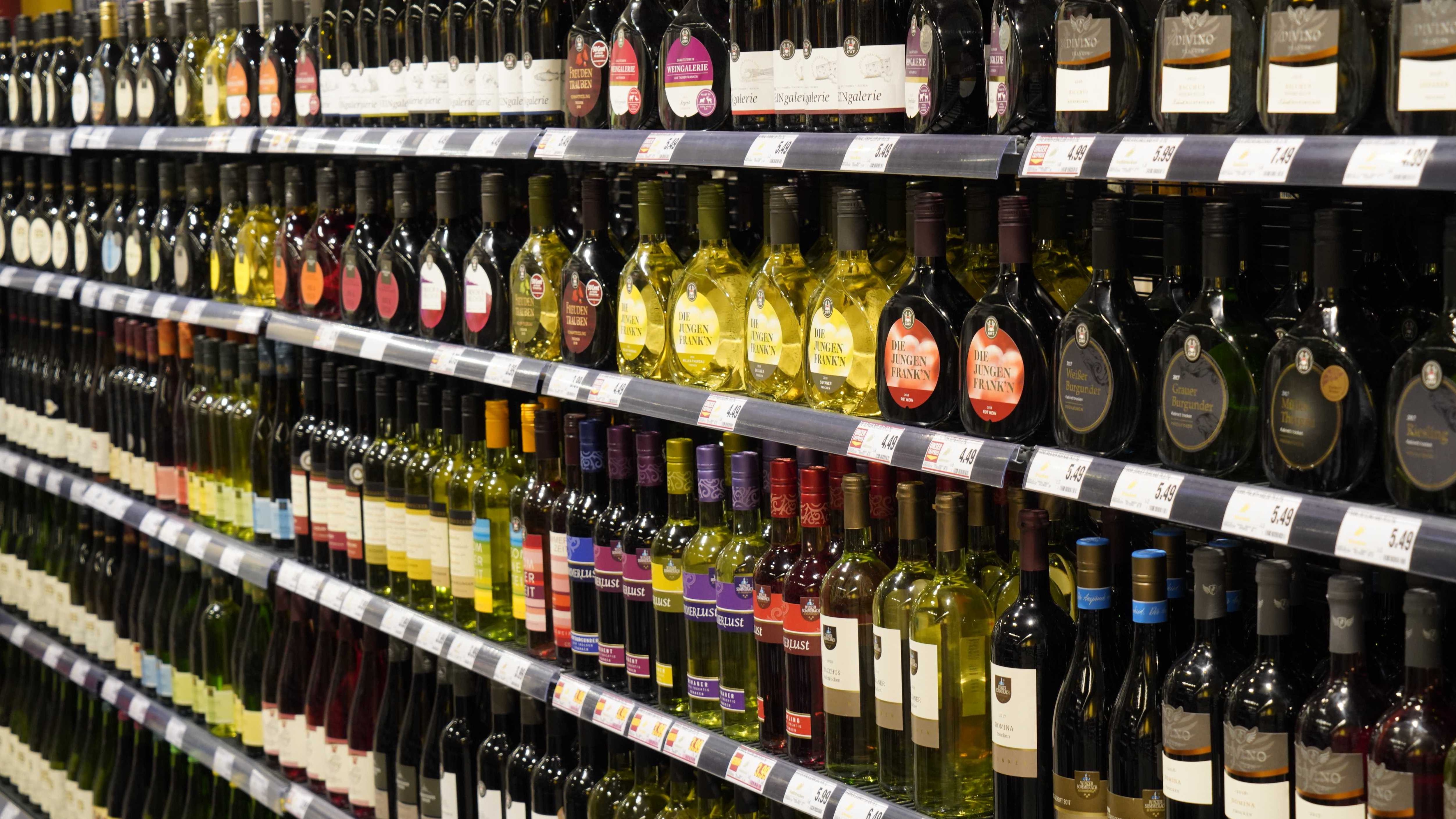 Unterschiedliche Weinsorten stehen aufgereiht in einem Regal in einem Edeka Center.
