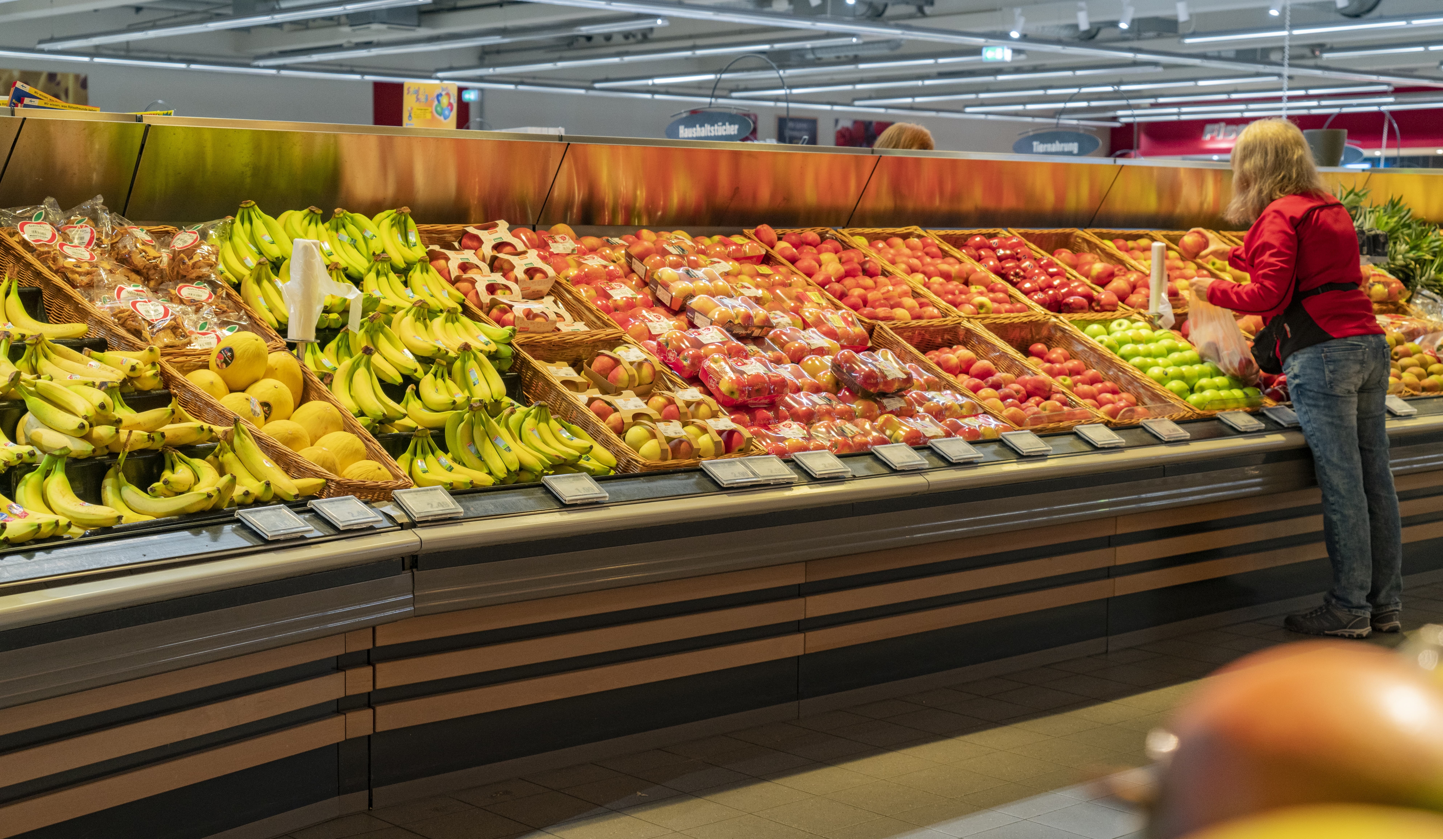 Eine Kundin bedient sich in der Obstabteilung eines EDEKA-Markts bei den Äpfeln.