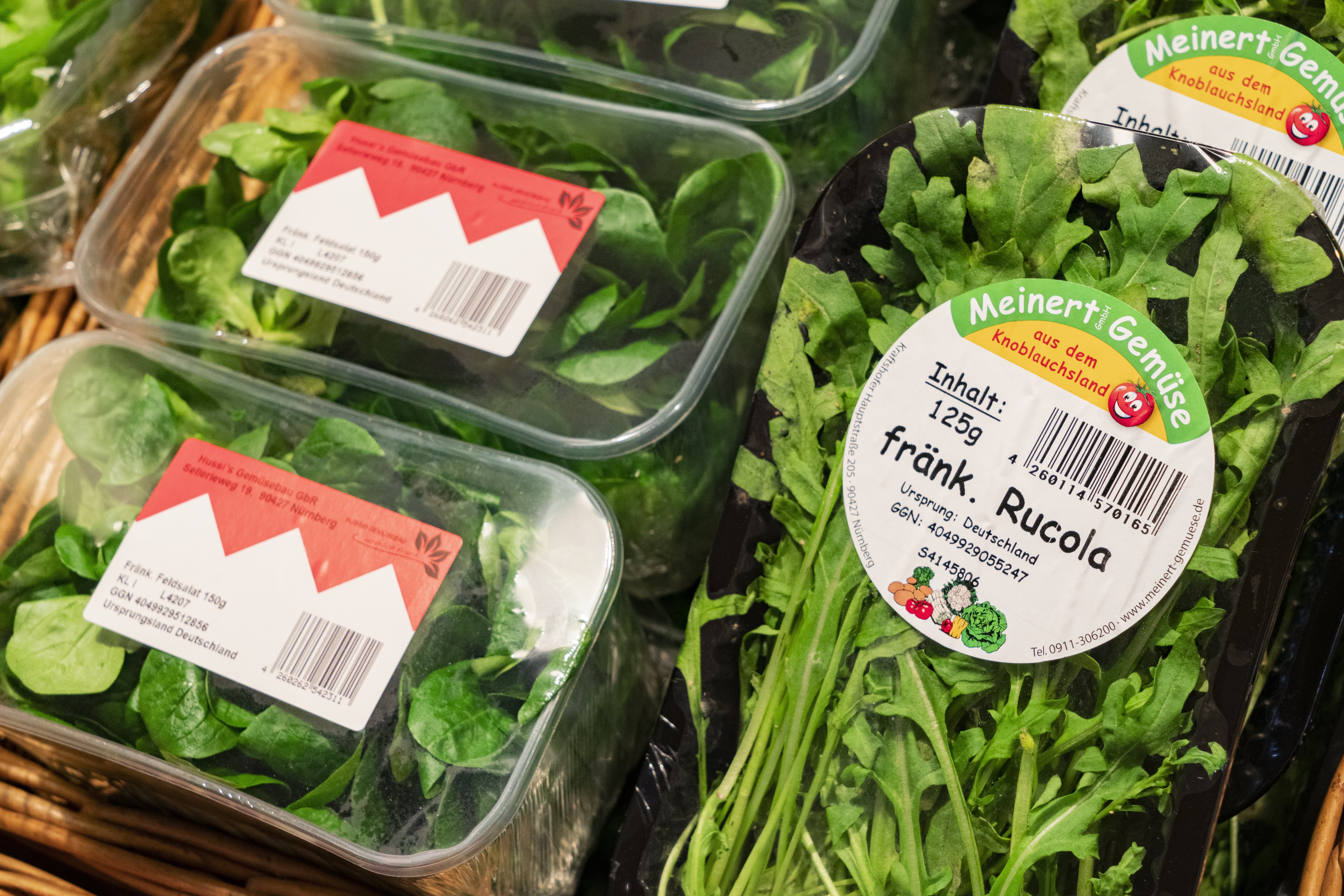 Verpackte grüne Salate (Spinat und Rucola) im Close-Up in einem EDEKA-Markt. Es handelt sich laut Etiketten um regionale Produkte.